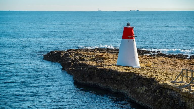 Phare rouge et blanc sur un rocher au bord de la Méditerranée